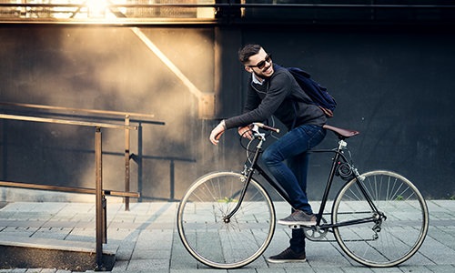 A man is sitting on his bike on a sidewalk 